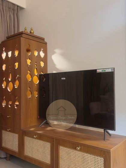 A close-up of a custom TV unit with an attached pooja mandir. The mandir features intricate jali work that allows light to filter through, while the console has cane-fronted shutters for a touch of ethnic charm.