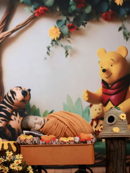 A peaceful newborn, wrapped snugly in a yellow blanket, sleeps in a wagon within our charming Winnie the Pooh themed set.