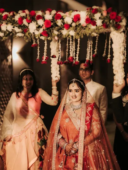 The bride's entrance is a moment of anticipation and beauty. I capture her gentle smile as she walks under the 'phoolon ki chadar', with the warm glow of the evening lights creating a magical atmosphere.
