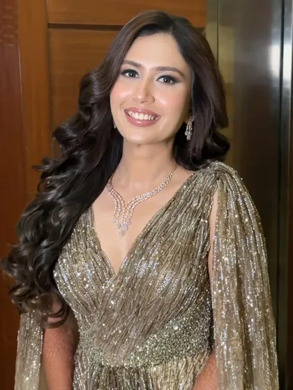 The perfect smile to complete a glamorous Sangeet look. This full view showcases how the soft, glowing makeup and voluminous curls come together with the shimmering gown for a cohesive and stunning bridal style.
