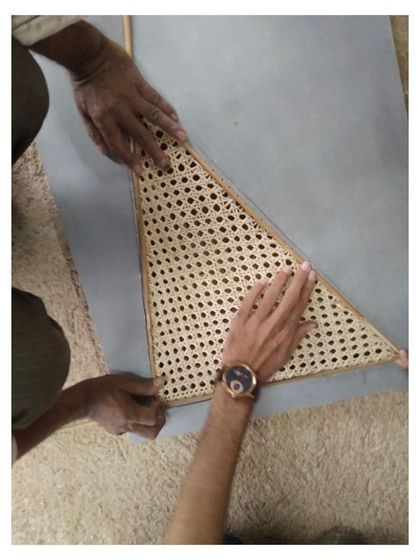 A craftsman carefully fits a handwoven cane panel. This focus on handmade details and natural materials is central to my design philosophy, adding soul and authenticity to each piece of furniture.