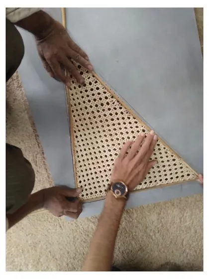 A craftsman carefully fits a handwoven cane panel. This focus on handmade details and natural materials is central to my design philosophy, adding soul and authenticity to each piece of furniture.