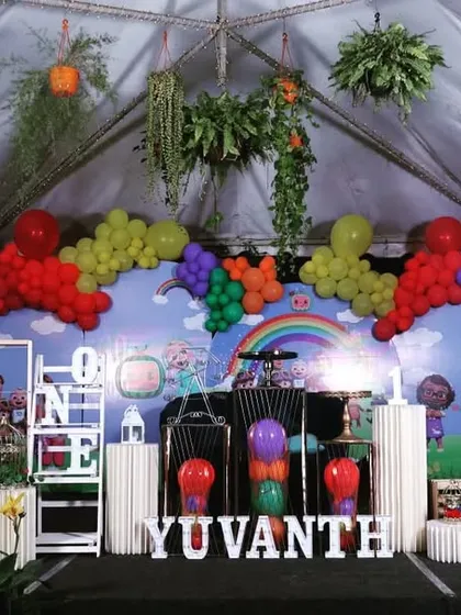 The full stage setup for a Cocomelon-themed birthday party, complete with colorful balloons and character cutouts.