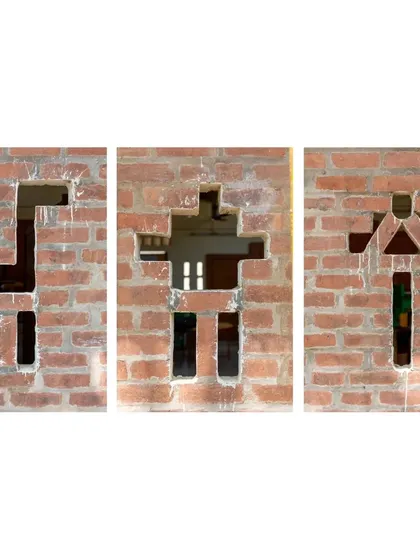 Playful openings in the brick wall of the Spastic Society classroom. These shapes, resembling animals and people, were created by strategically leaving out bricks, a simple yet creative way to add character and ventilation using a basic material.