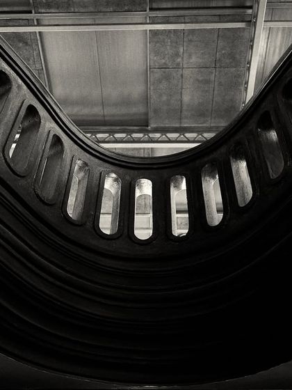 An abstract, worm's-eye view of the curved balcony, emphasizing its form and the repetition of the carved openings.