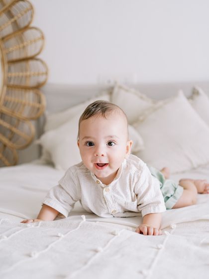 A happy seven-month-old boy enjoying his tummy time on a soft bed. His bright smile lights up the room.