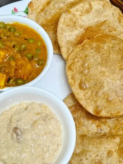 A complete meal plate featuring our delicious Matar Paneer, fluffy puris, and a side of kheer.