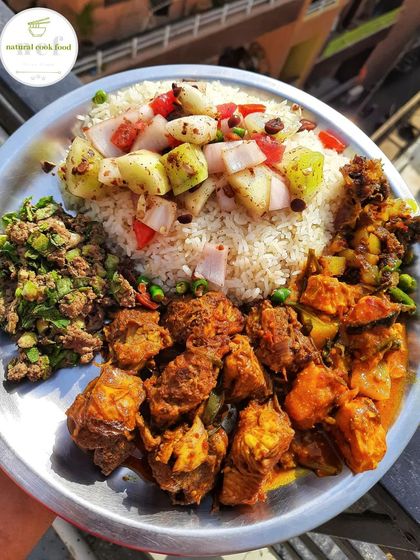 A complete meal with spicy liver chutney, fresh salad, chicken curry, fish curry, and a fish head stir fry.