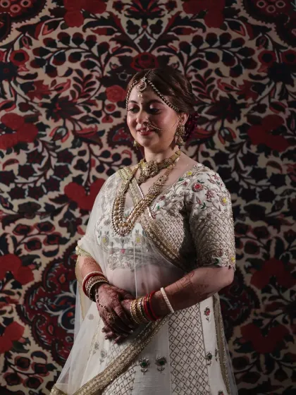 A portrait of poise and elegance. The bride's serene expression is complemented by the soft, glowing makeup and the rich patterns of her lehenga and the backdrop.