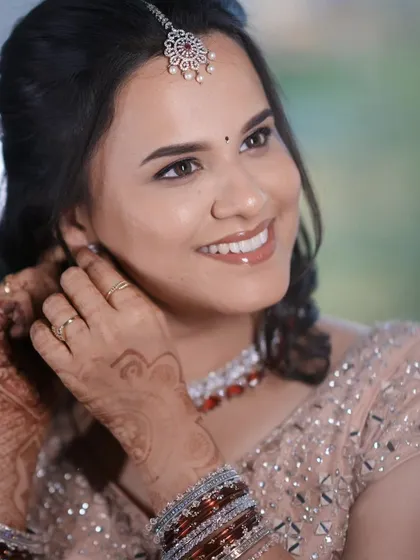 Dr. Krishnaveni getting ready for her reception. This candid shot captures her happiness and the beautiful details of her makeup and jewelry.