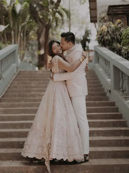 The couple shares a sweet kiss on the cheek while embracing, a perfect candid moment from their pre-wedding session.