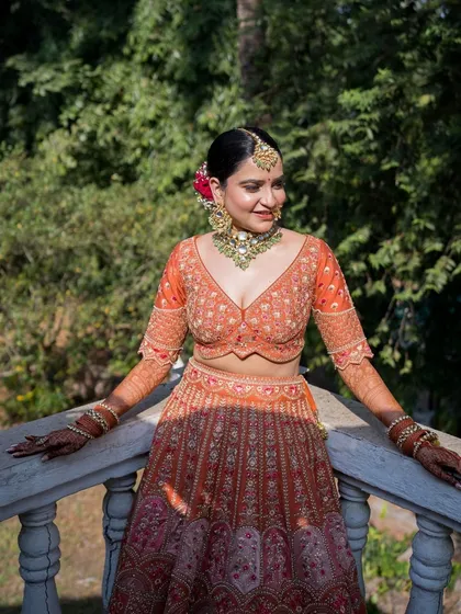 A dreamy bridal makeup look for a daytime wedding. The bride is glowing in her orange lehenga, with soft, radiant makeup to match.