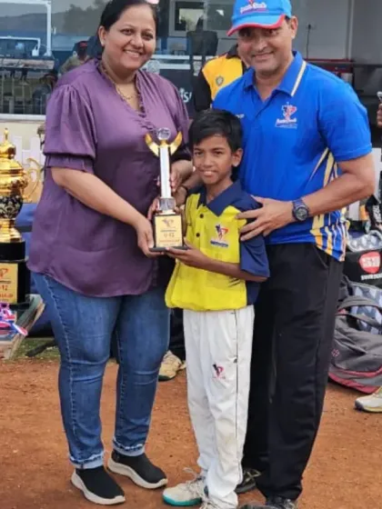 A family moment, as a young player receives his trophy alongside his parents and coach, celebrating the support system behind every cricketer.