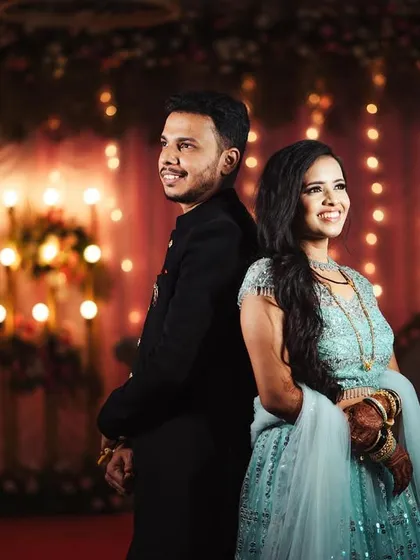 Shweta and Onkar standing back-to-back against a backdrop of twinkling lights. This classic pose is elevated by the beautiful bokeh, creating a festive and romantic atmosphere.