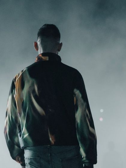 A dancer from "To Da Bone" seen from behind, facing the stage lights. This artistic shot creates a sense of mystery and anticipation.