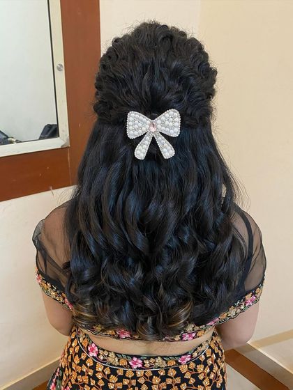A cute and modern hairstyle with soft curls and a half-up twist, secured with a pearl and crystal bow clip.
