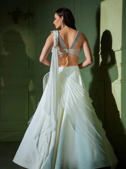 The back of the white ruffled gown, showcasing the intricate strap design of the blouse and the beautiful texture of the draped fabric.