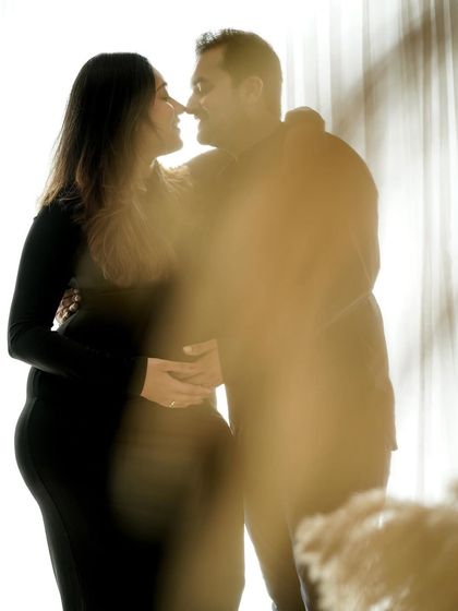 An artistic shot of a couple's intimate moment, captured through a soft, golden foreground for a dreamy effect.