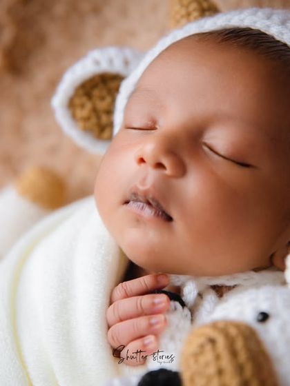 A peaceful close-up of the newborn's face in the cow hat, showing his delicate features.