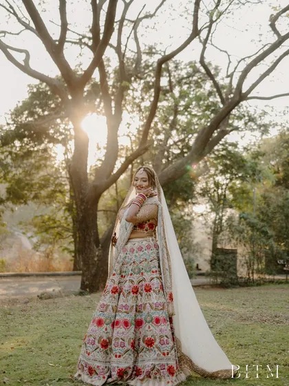 A bride stands under a majestic tree, bathed in the golden light of the setting sun. This portrait is romantic and serene, a perfect capture of bridal beauty in nature.