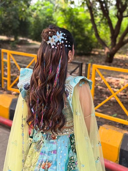 A back view of the carnival hairstyle, showing the full effect of the half bun, floral clips, and colorful threads. It's a true statement look.