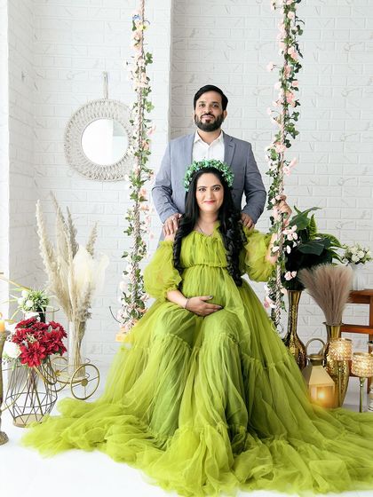 A happy couple's portrait on our floral swing set. The mom-to-be is glowing in a lime green tulle gown, perfectly complementing the bright and cheerful studio atmosphere.