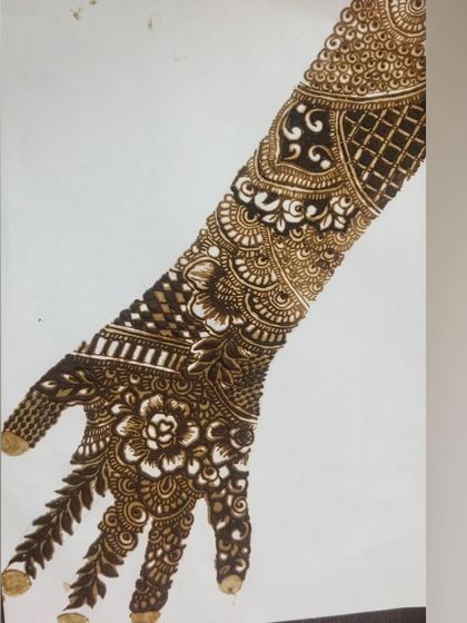 A practice design on a template, showcasing a full bridal arm pattern. This demonstrates the level of detail and planning that goes into creating a complex and beautiful bridal mehendi.