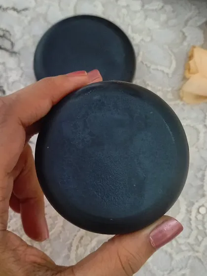 Holding a bar of my Activated Charcoal & Tea Tree Oil soap. This was one of the first soaps I created to solve my own skin issues, and it remains a bestseller.