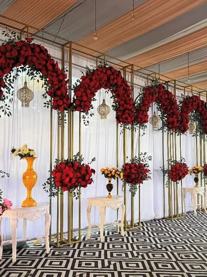 Nothing says romance like a wall of red roses. We designed this dramatic stage backdrop with golden frames and cascading arches of deep red flowers, creating a luxurious and unforgettable setting for a wedding or grand anniversary celebration.