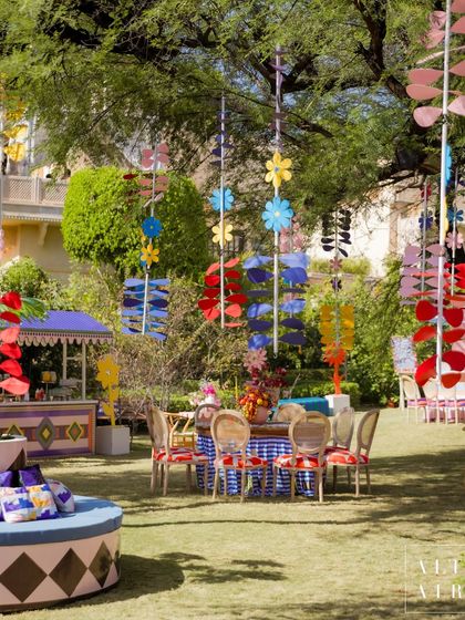 An overview of the seating at 'The Roots' Mehendi, with colorful hanging installations and patterned tablecloths. The design celebrated identity, play, and storytelling.
