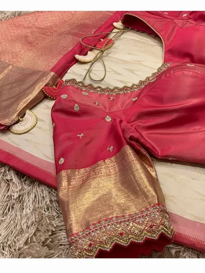 A close-up of the red embroidered blouse, showing the cutwork sleeve detail and the custom tassels on the saree.