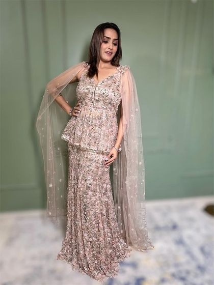 A side view of this elegant peplum gown, showcasing the delicate cape and fitted silhouette. It's a sophisticated and fashionable rental option.