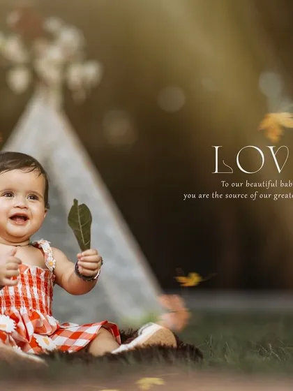 A beautiful autumn-themed outdoor portrait of a happy baby girl playing with a leaf.