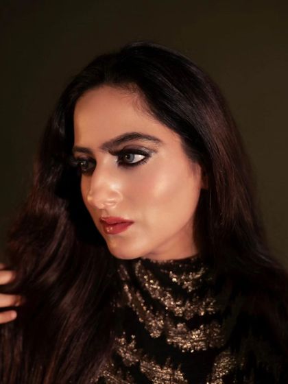 A dramatic and moody portrait. The play of light and shadow across the model's face creates a sense of mystery and highlights her striking features and bold makeup.