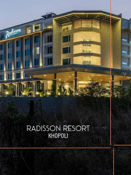 The contemporary facade of Radisson Resort, Khopoli, illuminated at dusk. The architecture balances clean lines with warm, inviting lighting, establishing its presence as a modern urban resort nestled in a natural landscape.