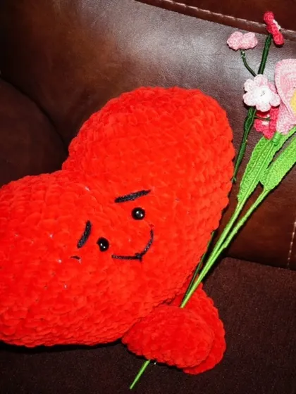 The red sweetheart plushie, looking dapper while holding a bouquet of handmade flowers.