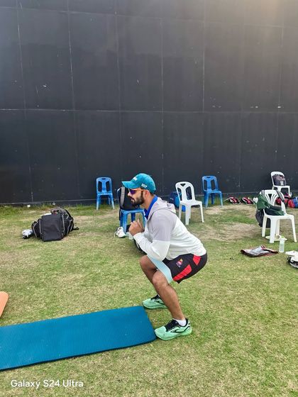 Performing bodyweight squats during an on-field warm-up. This fundamental movement activates the glutes and quads, preparing the lower body for the explosive movements required in sprinting, jumping, and fielding.