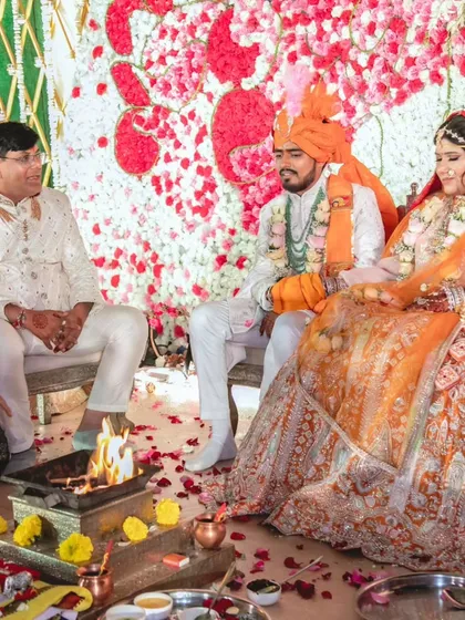 A moment of tradition and love under a canopy of flowers. This setup shows the sacred fire at the center of the mandap, with a backdrop of red and white roses creating a vibrant and auspicious atmosphere.