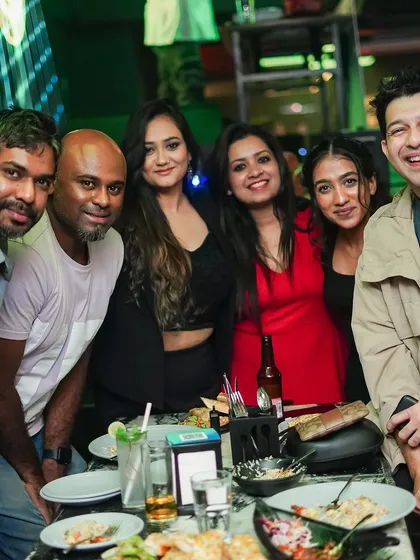 A group of friends enjoying food and drinks at their table.
