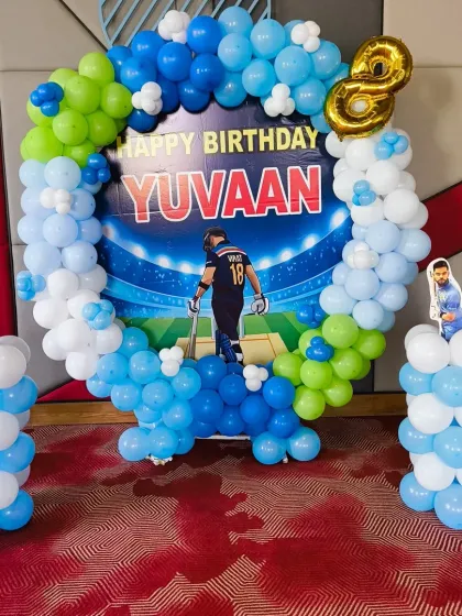 The main photo area for the cricket party featured a personalized backdrop with the birthday boy's name and age, framed by a circular balloon arrangement and flanked by themed balloon pillars.
