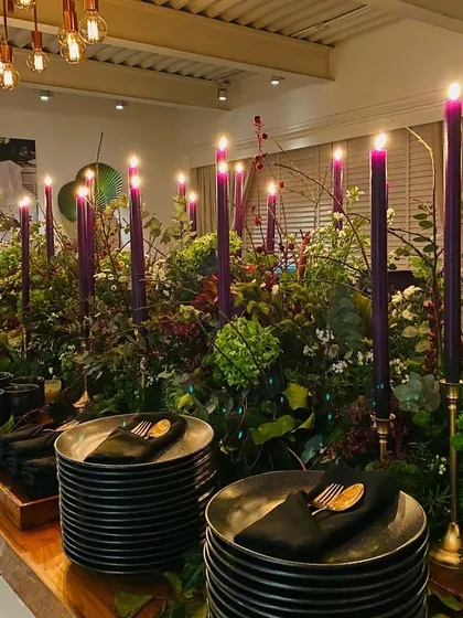 The place settings for the soirée, with black plates and napkins providing a chic contrast to the vibrant floral arrangements.