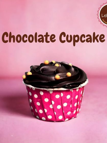 A classic Chocolate Cupcake, perfect for any occasion. It's a moist chocolate sponge topped with a rich swirl of chocolate frosting and a few crunchy pearls for decoration.