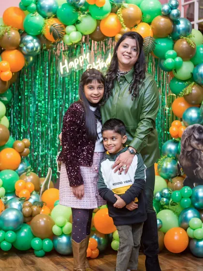 So much love in one frame! A mother and her children posing in front of the dinosaur-themed birthday decorations.