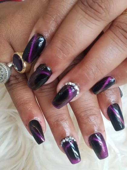 A close-up of the mesmerizing purple cat-eye effect on square nails, with rhinestone accents.