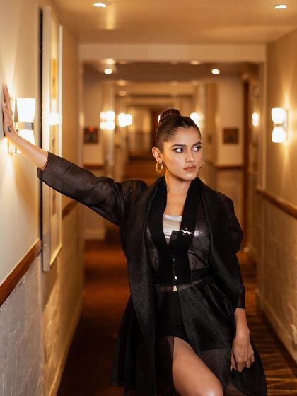 A creative pose using the architectural elements of the hallway. The play of light and shadow adds drama to this fashion shot, emphasizing the silhouette of the outfit.