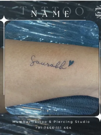 The name "Saurabh" with a small heart, inked in a clean, cursive font. We can add small symbols to any name tattoo to give it an extra personal touch.