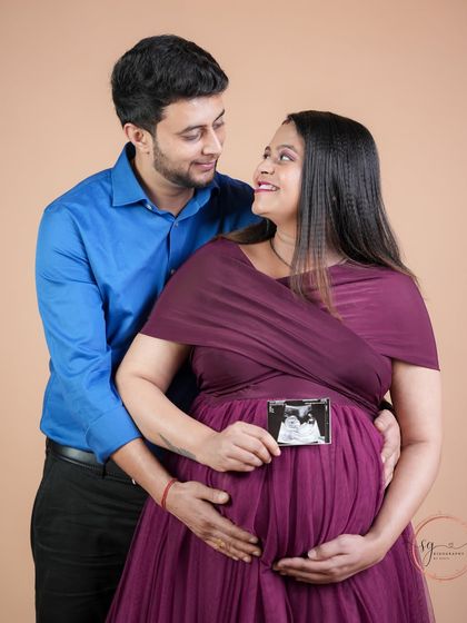 A sweet moment of shared excitement, with the couple holding the ultrasound picture together. Their loving gaze at each other tells a beautiful story.