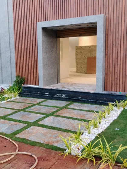 This is a modern commercial landscaping project I completed. The design features geometric stone pavers interspersed with grass, bordered by white pebbles and spider plants, creating a clean and welcoming entrance for the building.