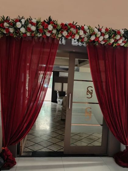 An elegant entrance for an engagement party, with deep red drapes and a thick floral border. This simple touch adds a lot of class to the venue's doorway.