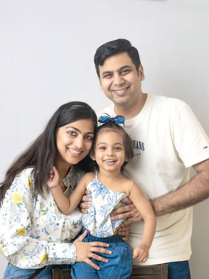 A bright and happy family portrait. The simple white background and casual outfits create a relaxed and approachable feel.